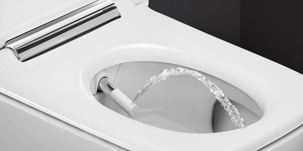 Ein modernes Bidet mit einem Wasserstrahl, der aus der Düse spritzt, auf einem weißen Toilettensitz.