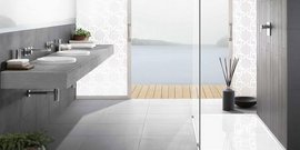 Ein modernes Badezimmer mit einem großen Waschbecken und Blick auf einen ruhigen See durch große Glastüren.