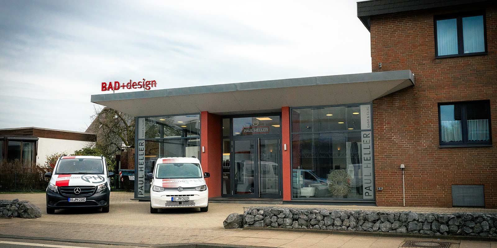 Die moderne Fassade eines Geschäfts mit dem Namen 'PAUL HELLER' und dem Logo 'BAD+design' ist gut sichtbar.
