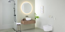 Ein modernes Badezimmer mit einer großen runden Spiegelleuchte, einem Holzwaschtisch und einer eleganten Dusche.