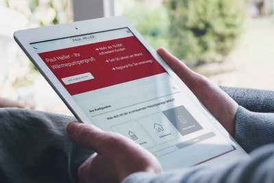 Eine Person hält ein Tablet, auf dem eine Webseite mit Informationen zu Wärmepumpen angezeigt wird.