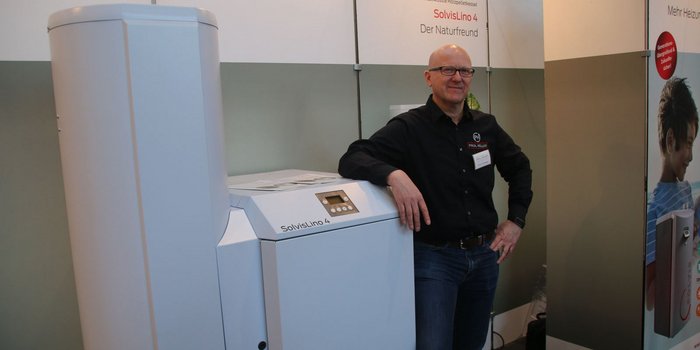 Der Aussteller präsentiert stolz die Heiztechnologie 'SolvisLino 4', während im Hintergrund ein Kind zu sehen ist.