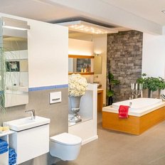 Ein modernes Badezimmer mit einer eleganten Badewanne, einem stilvollen Waschbecken und einer großen Pflanze im Vordergrund.