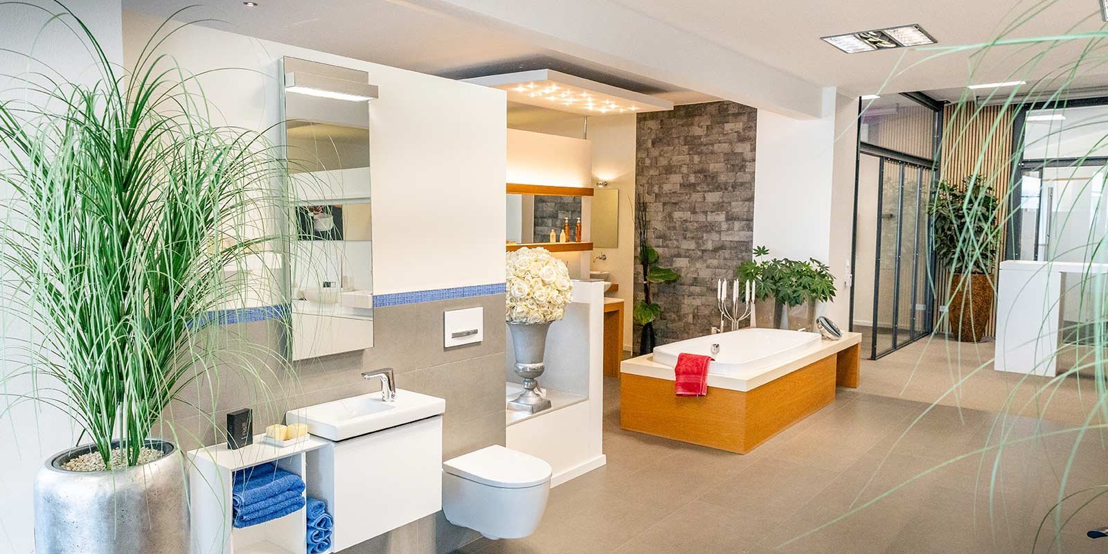 Ein modernes Badezimmer mit einer eleganten Badewanne, einem stilvollen Waschbecken und einer großen Pflanze im Vordergrund.