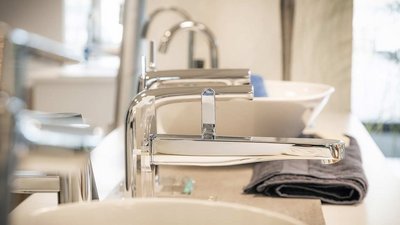 Ein elegantes Badezimmer mit glänzenden Wasserhähnen und einem weißen Waschbecken, das auf einem modernen Waschtisch steht.