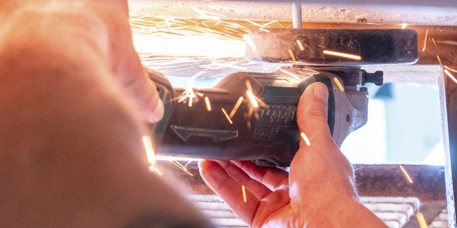 Ein Handwerker benutzt ein Elektrowerkzeug, während Funken in alle Richtungen sprühen, was eine dynamische Arbeitsatmosphäre schafft.